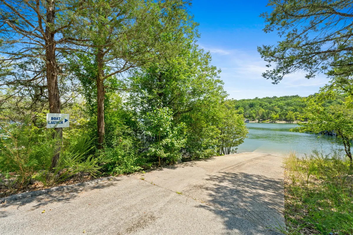 A concrete boat launch ramp with a clear sign indicating its use, surrounded by lush greenery and calm lake waters. The setting is tranquil, with easy access for launching boats or setting off for fishing and water sports, embodying the convenience and adventure described in the section.