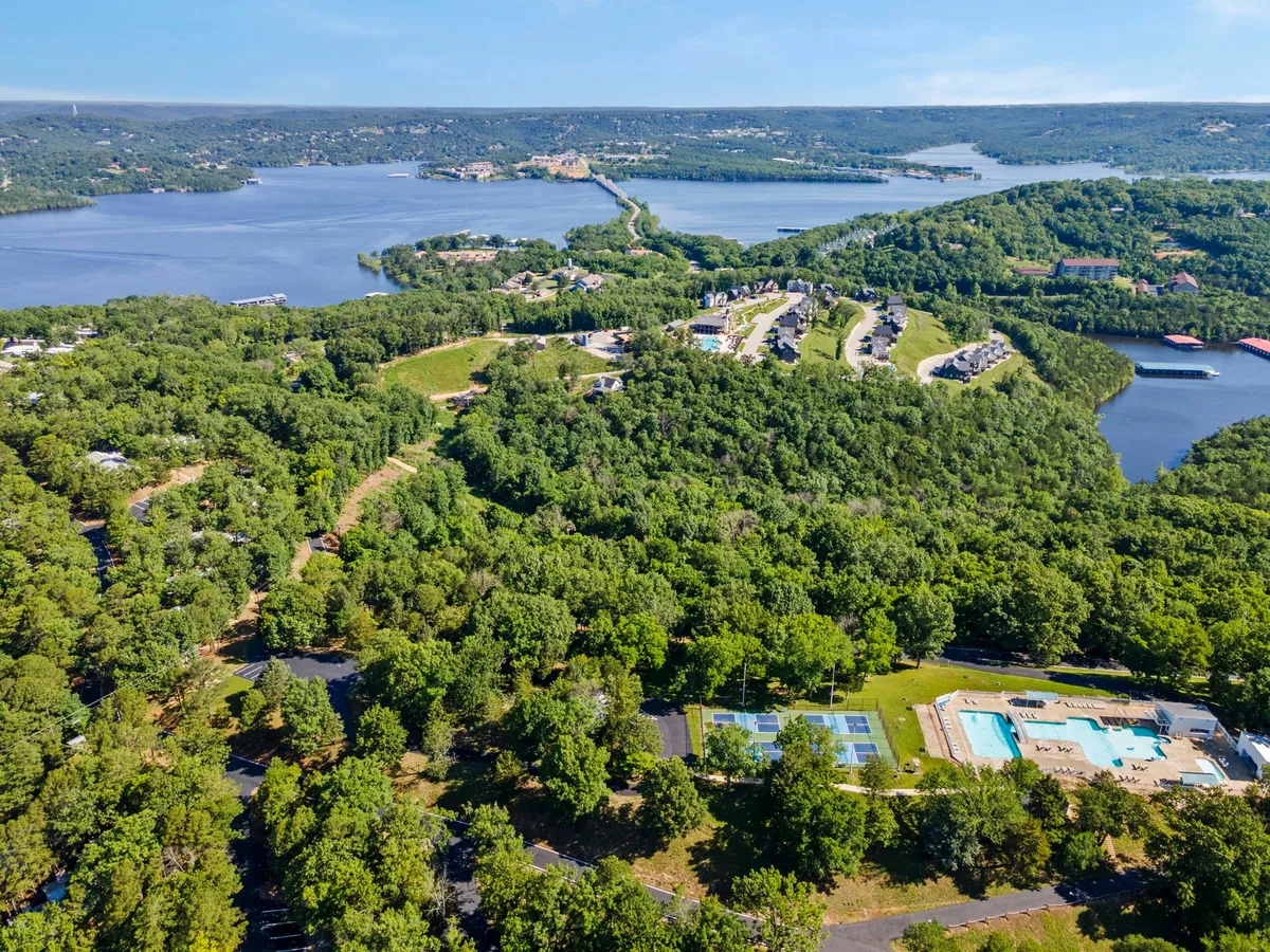 A wide-angle view of the sparkling lake surrounded by community amenities and residential areas, all set against a backdrop of lush greenery. The scene captures opportunities for swimming, hiking, and gathering, with the tranquil lake as the focal point.